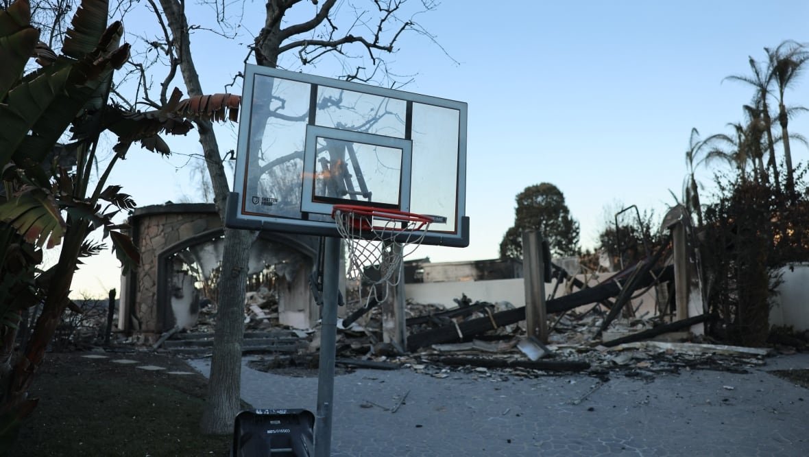 A basketball net remains on a damaged street.