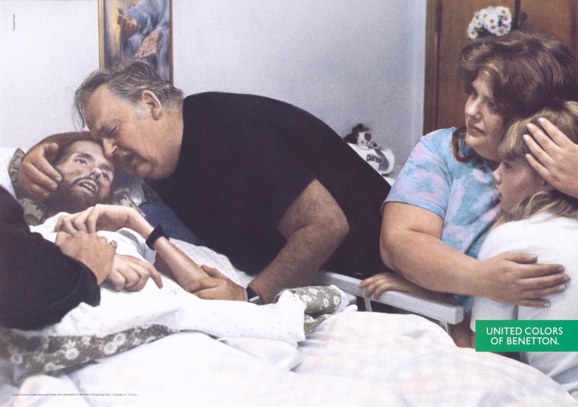 aids-david-kirby-ad-benetton-1992 A grey-haired man hugs the head of a bearding, ailing men in a bad as nearby a woman holds a young girl.