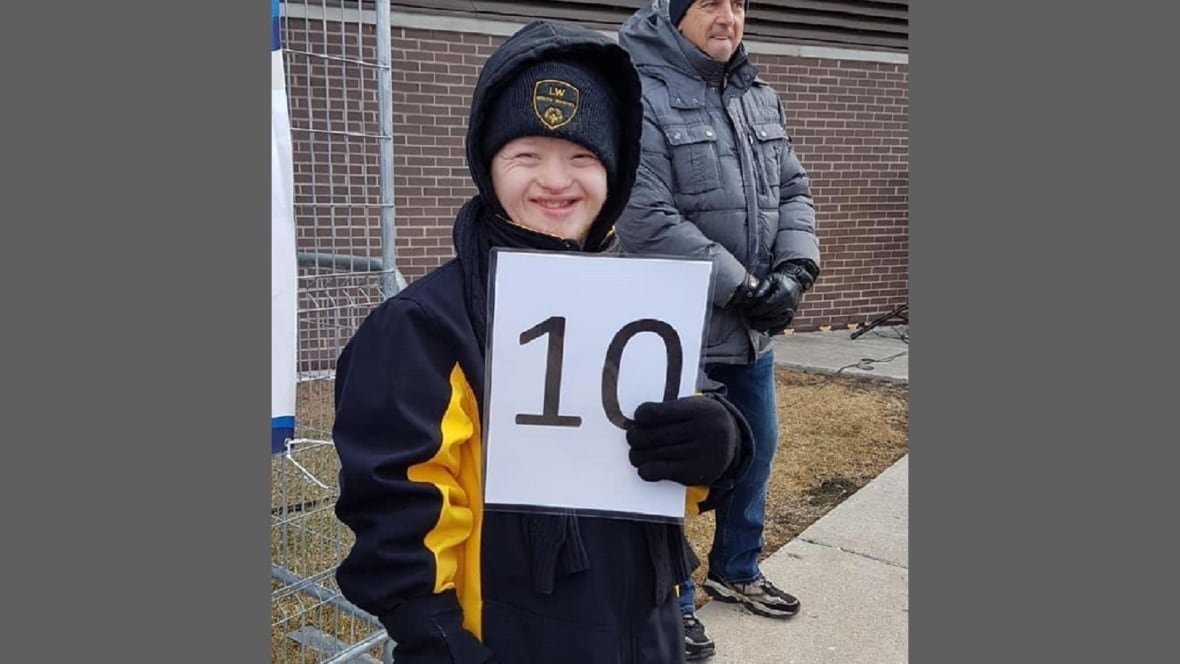 austin-clapp-1 An individual with Down Syndrome smiling and holding a scorecard.