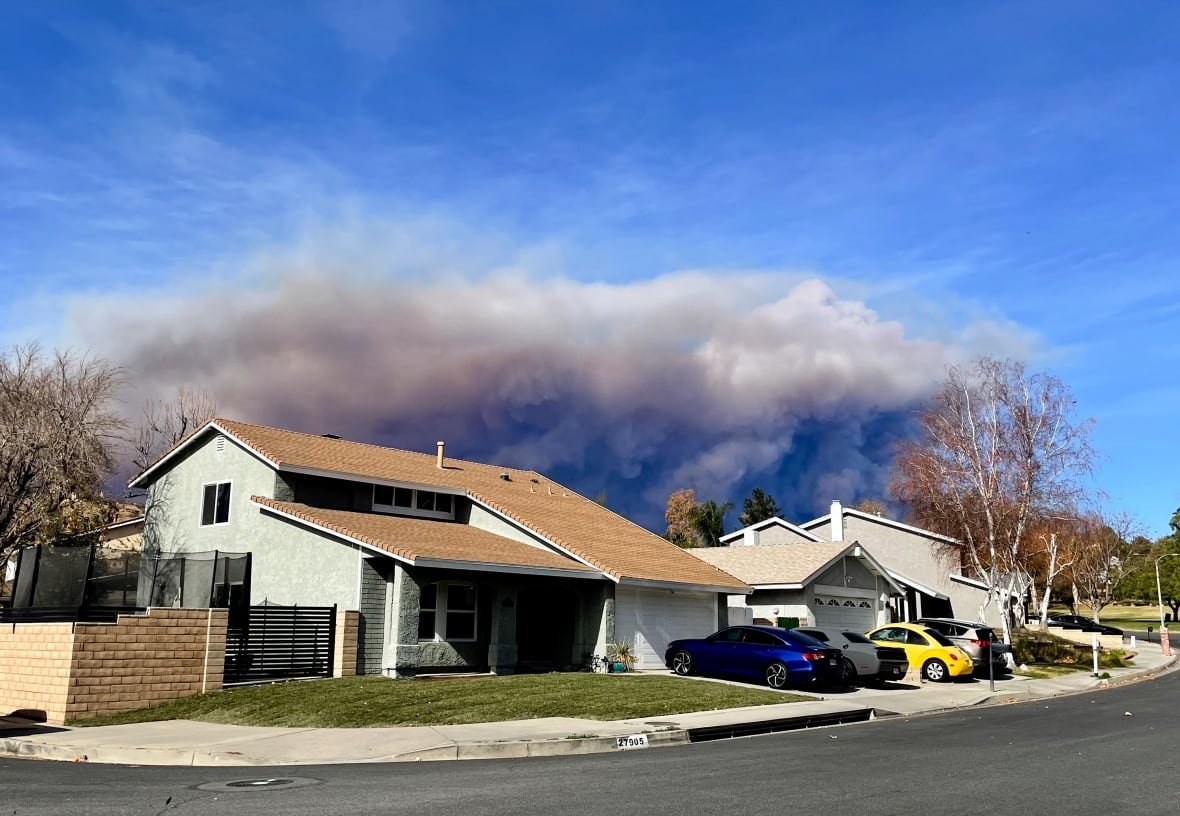 california-wildfires-49 A large plume of smoke rises behind a house.
