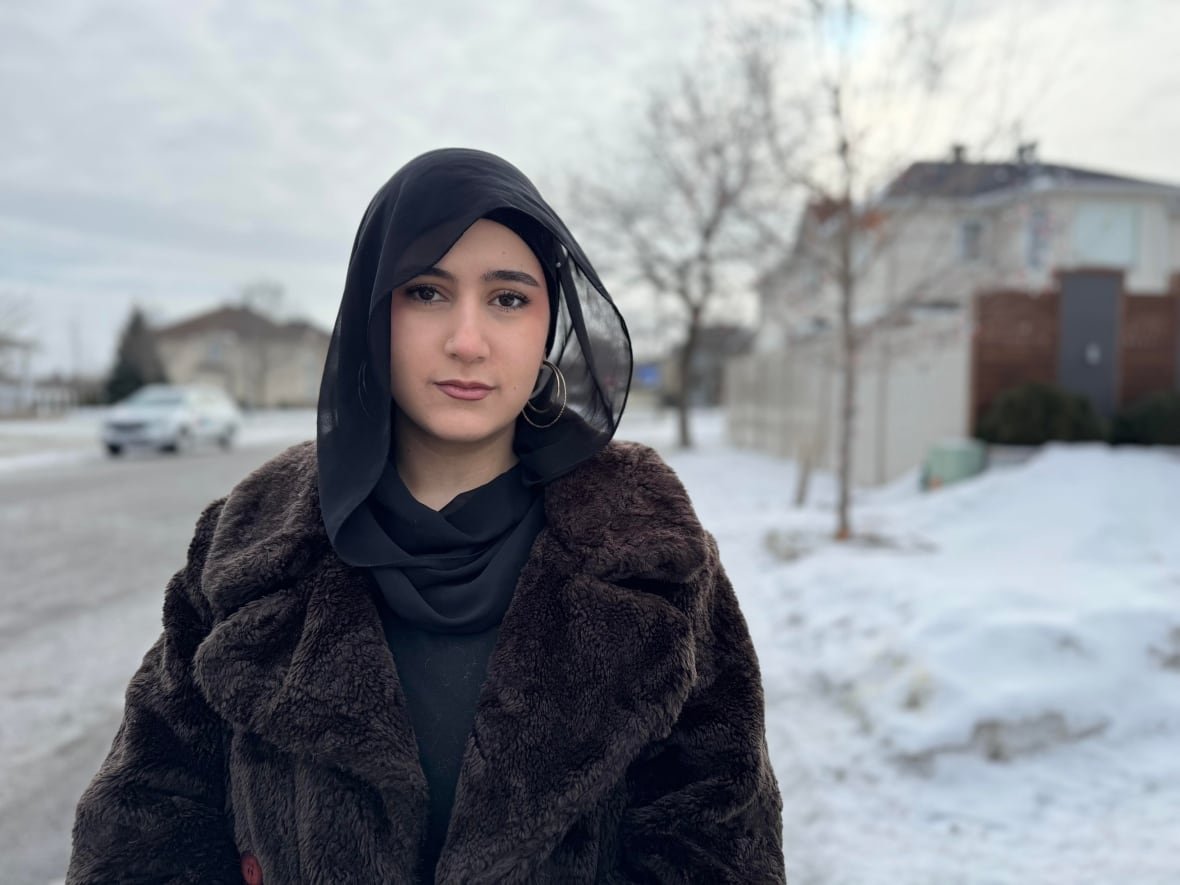 darine-alrajab a woman standing outside along a sidewalk surrounded by snow