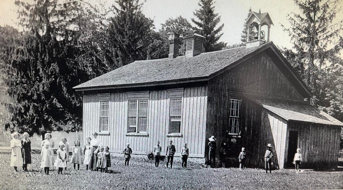 An old photo of a school with teachers and students out front