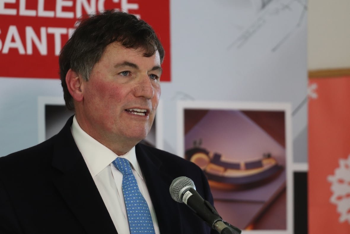 dominic-leblanc A man in a black suit and a blue tie speaking into a microphone.
