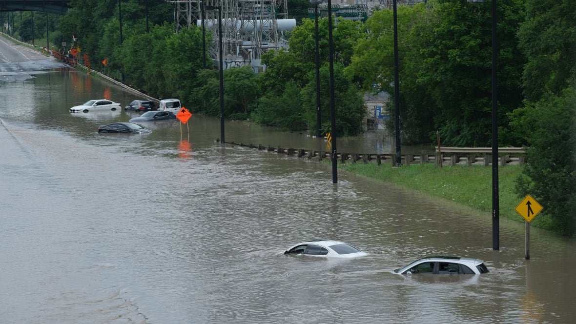 A number of cars lie on a totally flooded road.