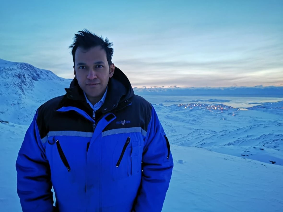 A man in a winter coat stands in a snowy area.
