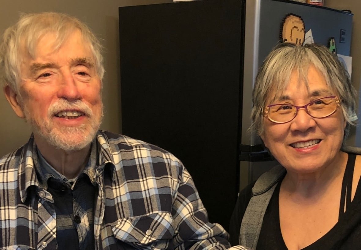 A man and wife sit in their kitchen at a table.