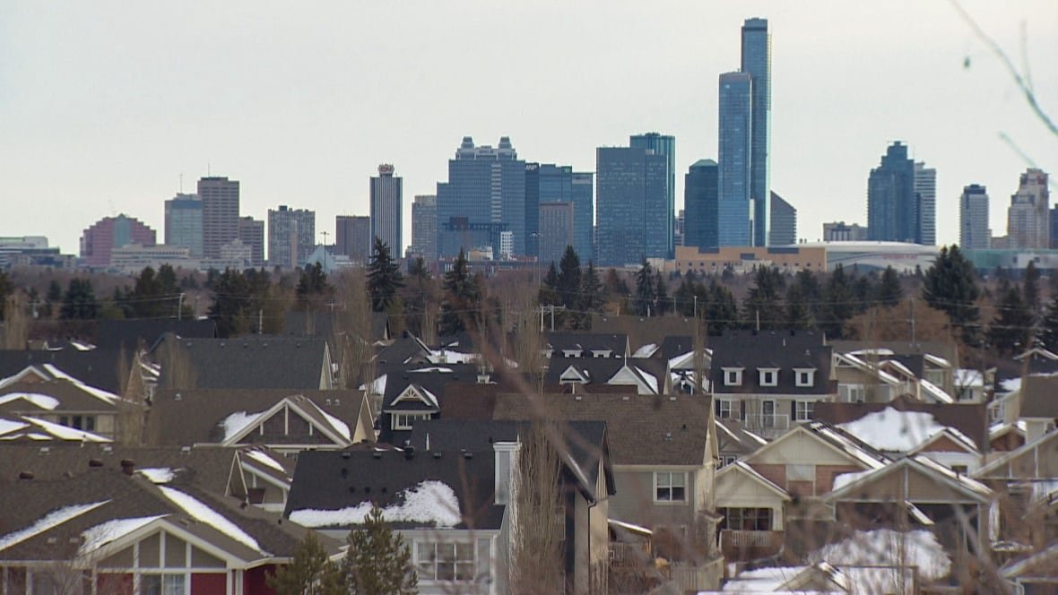 edmonton-1 Tall buildings stand beyond a wooded area and a suburban neighbourhood.