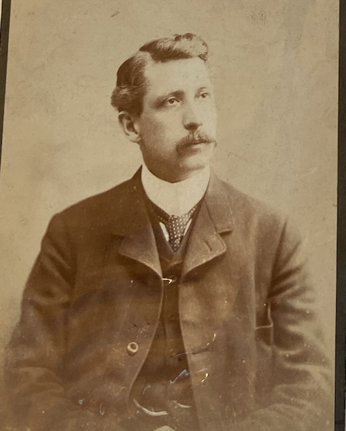 A portrait of a man with a moustache wearing a suit.