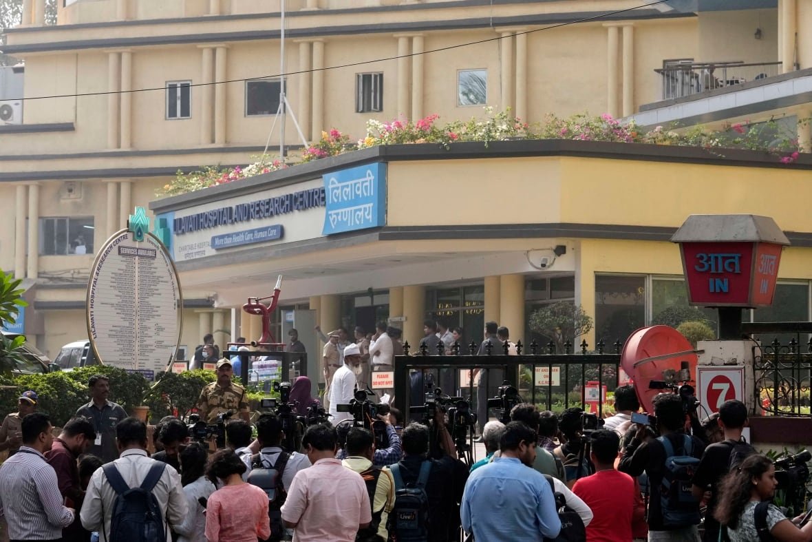 A group of people stand outside a gated building.