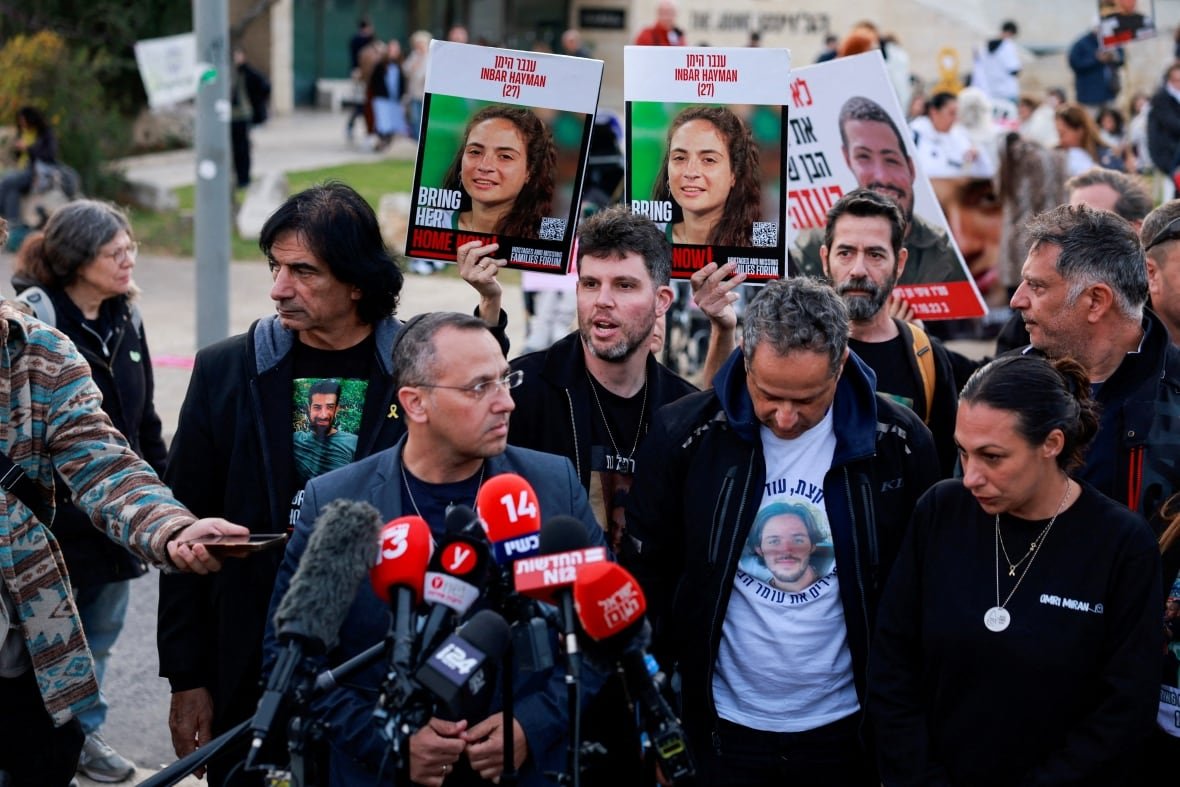 israel-palestinians-hostages-families Men and women at the front of a protest gather at a set of microphones.