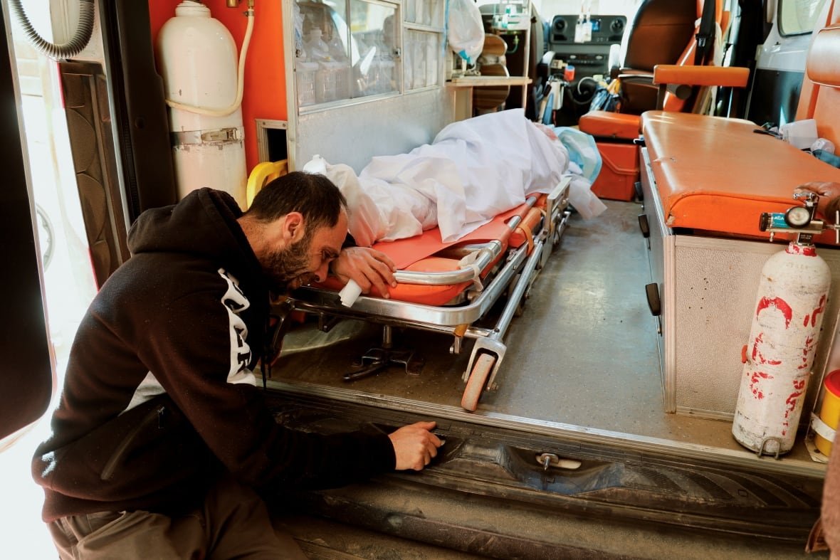 israel-palestinians-west-bank-jenin-raid A man cries over the body bag of his brother in an ambulance.