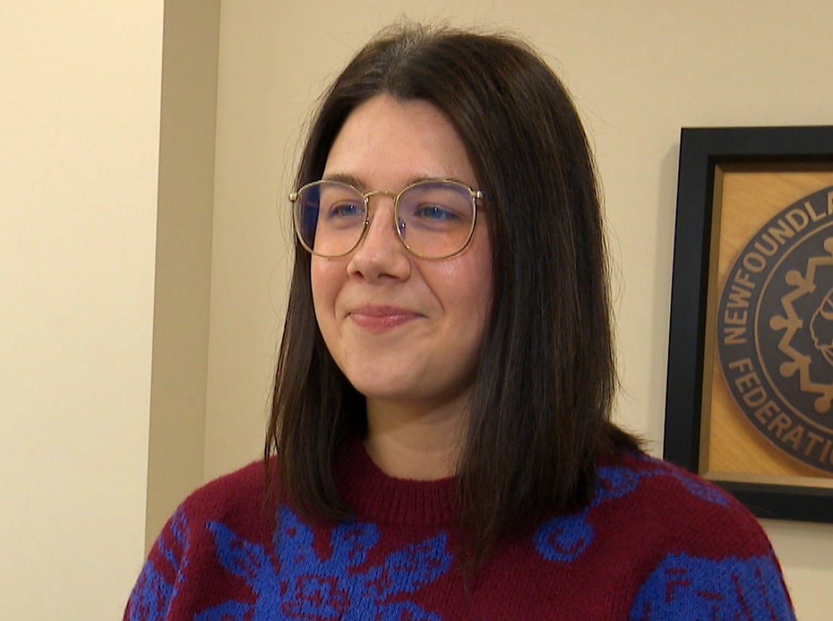 A woman wearing a red sweater with blue flowers on it.