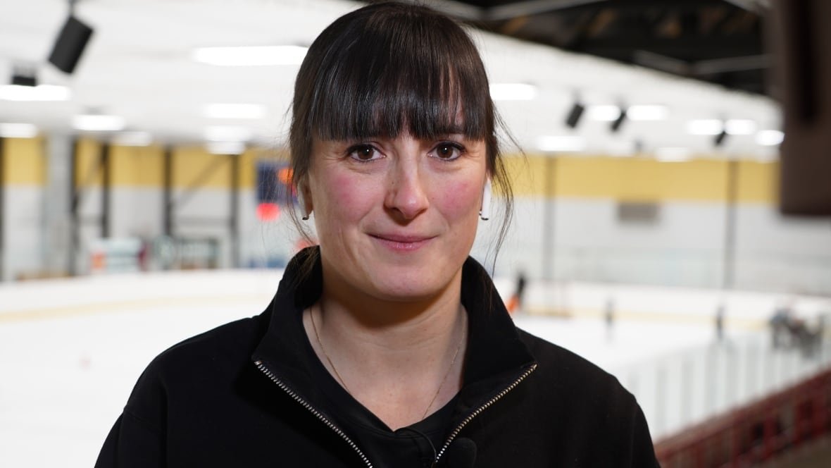 laurence-beaulieu A woman smiles at the camera, with an ice rink behind her.