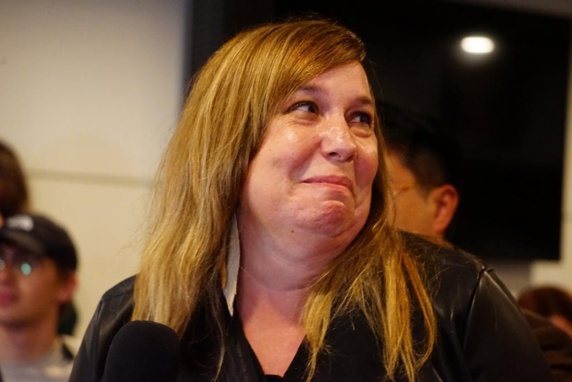 A woman, overcome with emotion, turns and smiles.