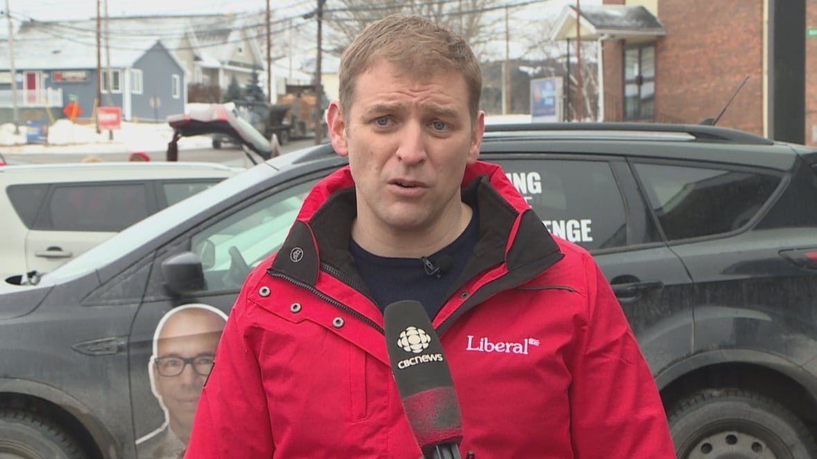 n-l-premier-andrew-furey-29-january-2021 Man with short hair wearing a bright red coat outside. There is a vehicle behind him.