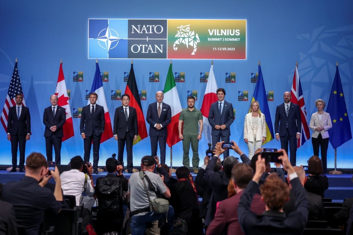 nato-summit Ten G7 leaders stand on stage with European leaders and Ukrainian President Volodomyr Zelenskyy in front of flags of various countries.