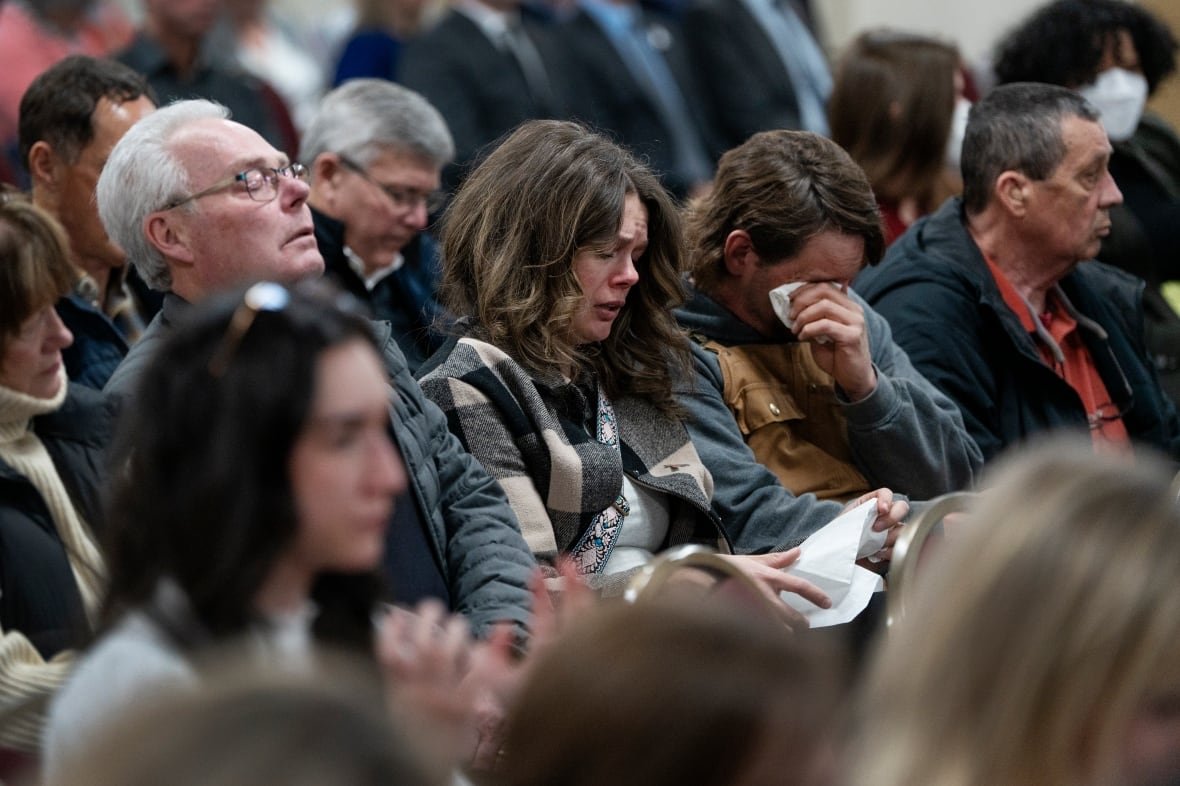 ns-mass-shooting-inquiry-20230330 Several people are seen crying and wiping away tears while seated.