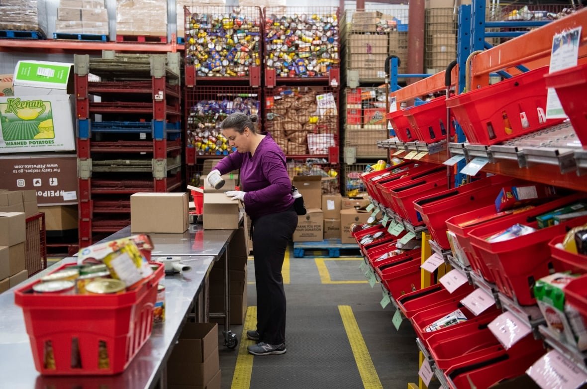 ottawa-food-bank-worker-covid-19-coronavirus-pandemic a woman sorting food at a large table in a warehouse