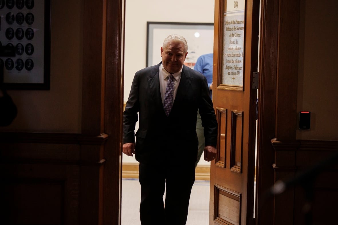 Man in a dark suit walks out of his office towards.