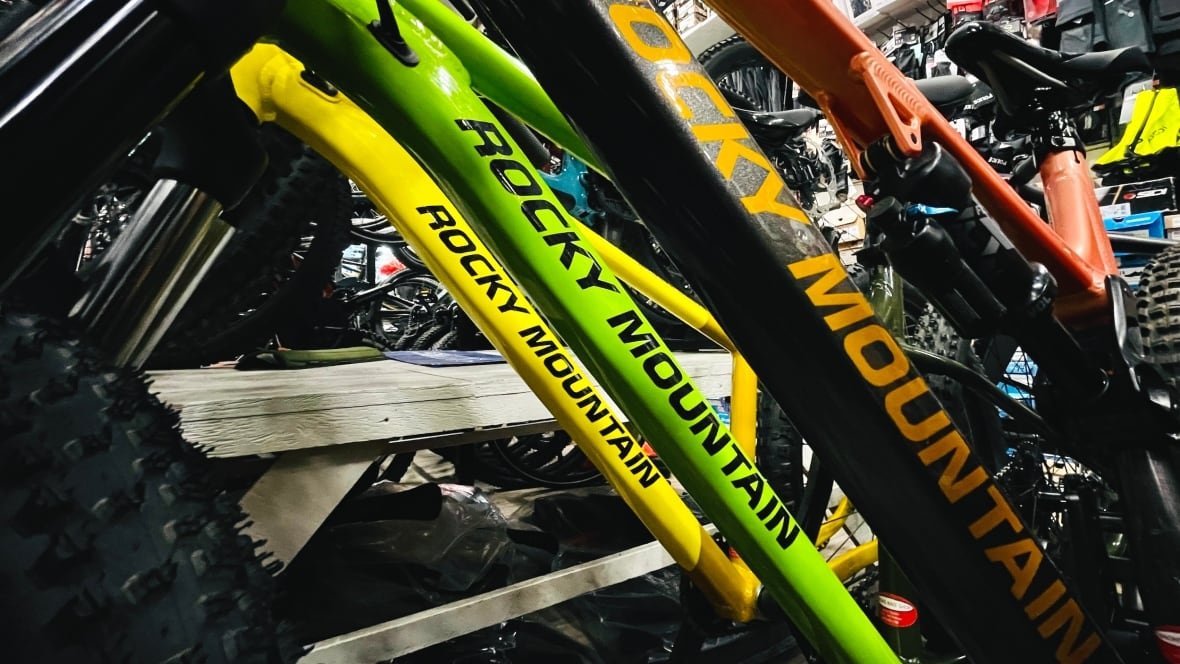 Three mountain bikes are pictured in a bike ship. They are yellow, green and black. Only parts of their frames are included in the photo.