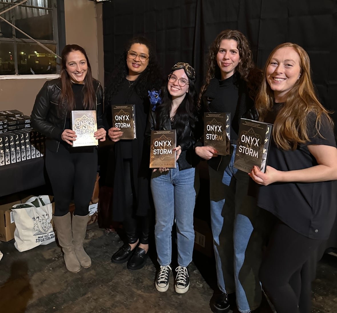 slow-burn Five women holding copies of the same book smile for the camera.