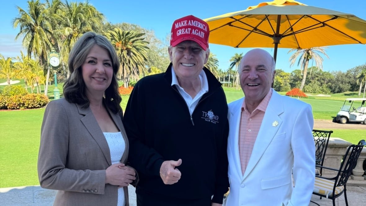 smith-trump-and-o-leary-1 A woman, and two men pose for a picture next to a sunny golf course.