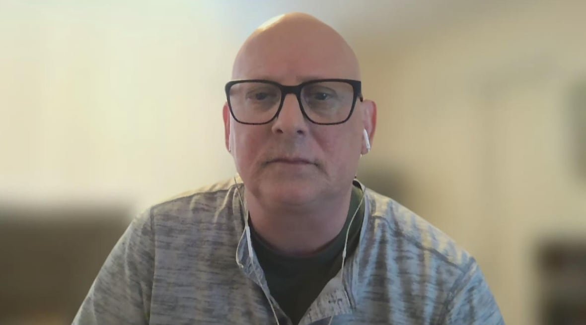 Man with glasses and grey sweater.