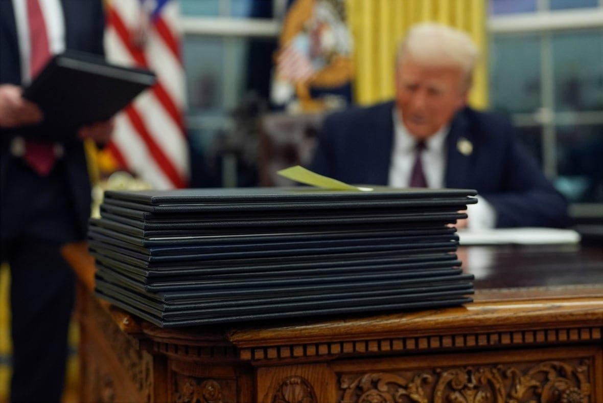 trump-inauguration-photo-gallery-2 A pile of documents in black folders are stacked on a wooden desk.