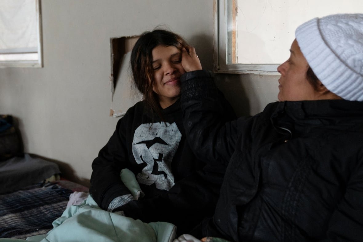 usa-trump-border-mother-1 A dark haired woman in white toque brushes the face of a younger person, also dark haired.