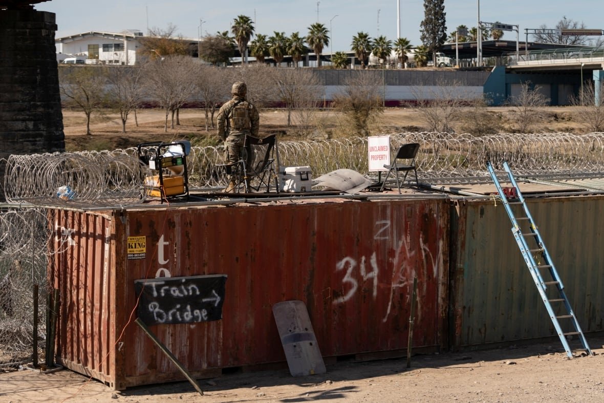 usa-trump-migration-mexico A U.S. National Guardsman stands atop a shipping container and looks across the border towards Mexico from Eagle Pass, Tex.