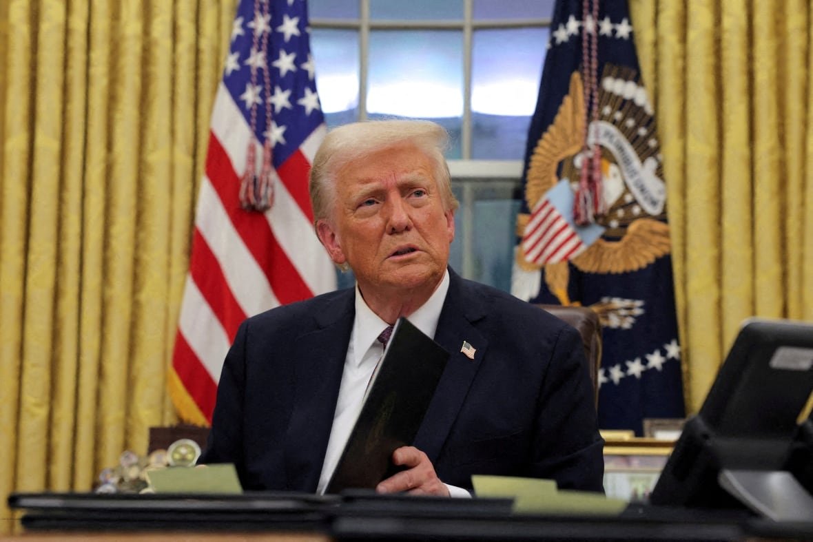 Trump sits at his desk in the oval office