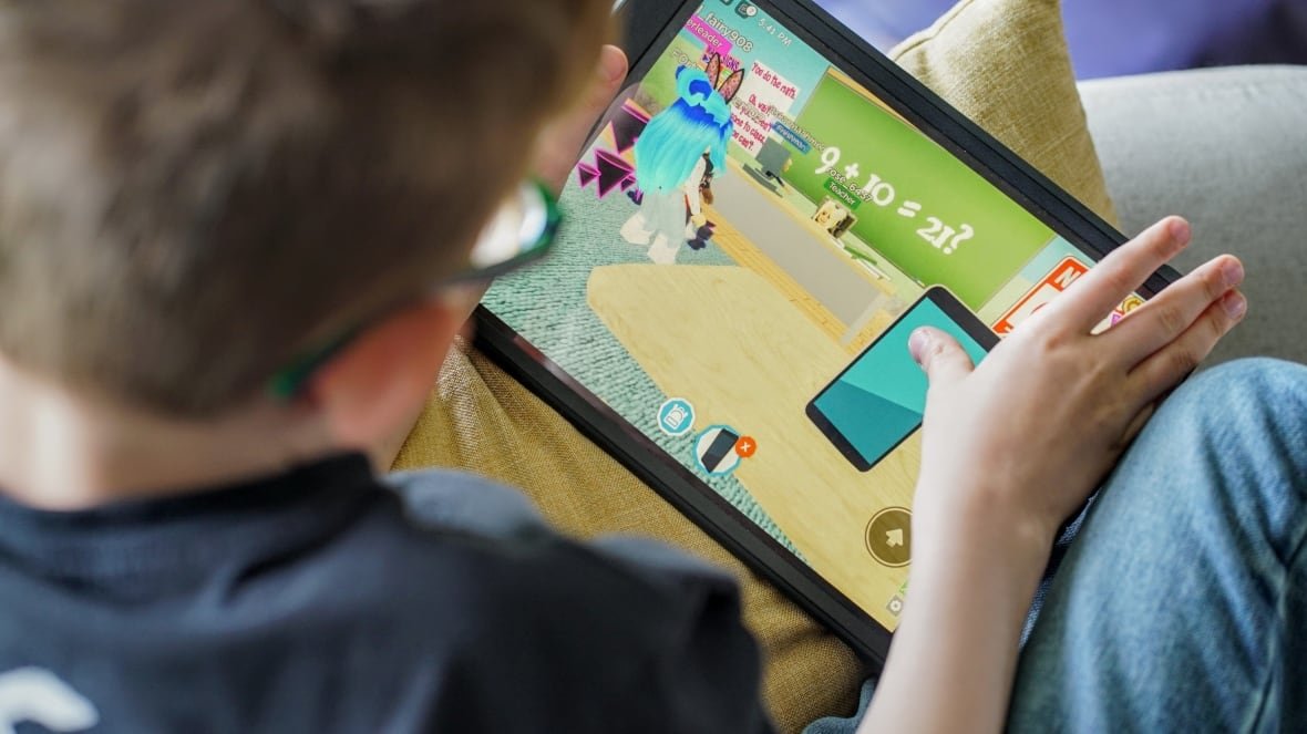 A young boy plays an iPad game with mathematical equations