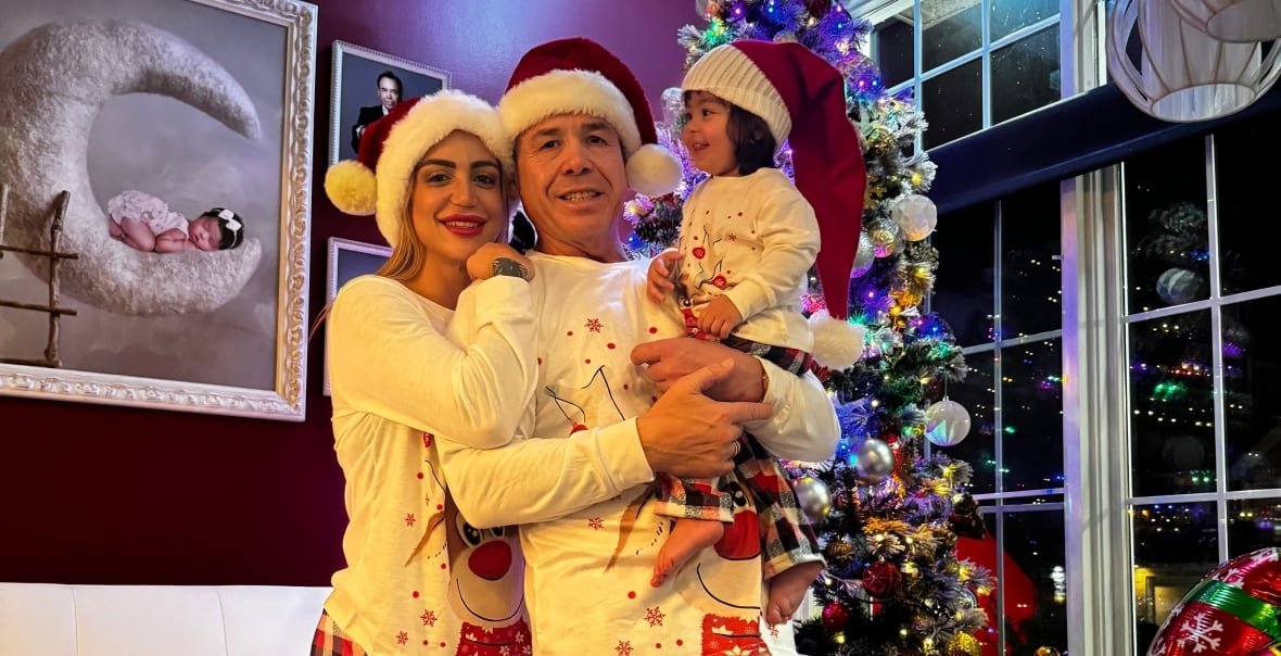 A man, woman and child pose for a Christmas family photo.