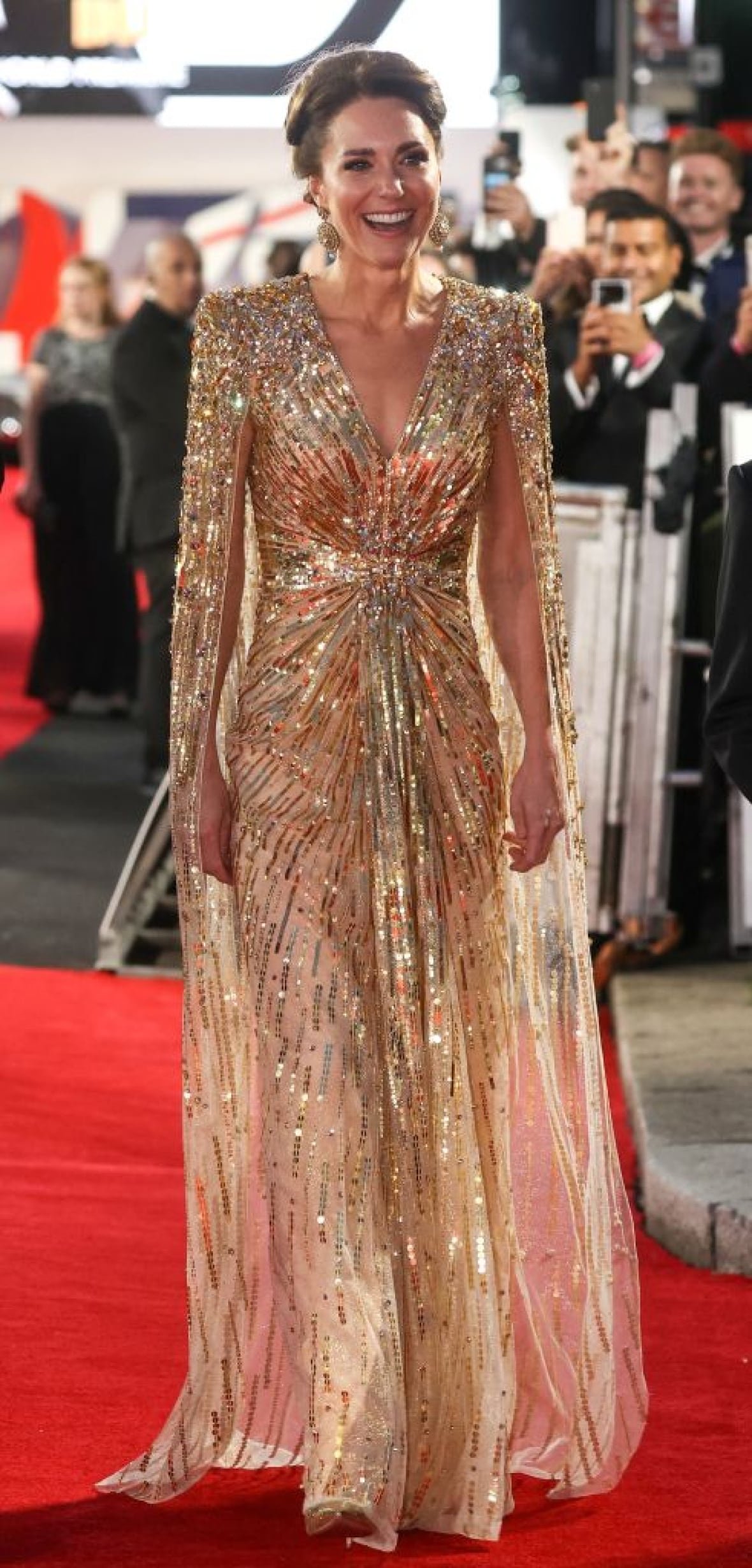 A person wearing a long dress walks on a red carpet.