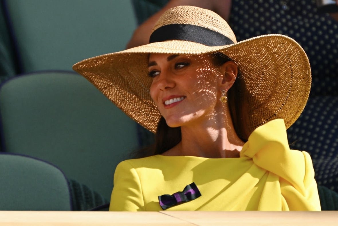 A person wearing a large hat sits in a sports stadium.