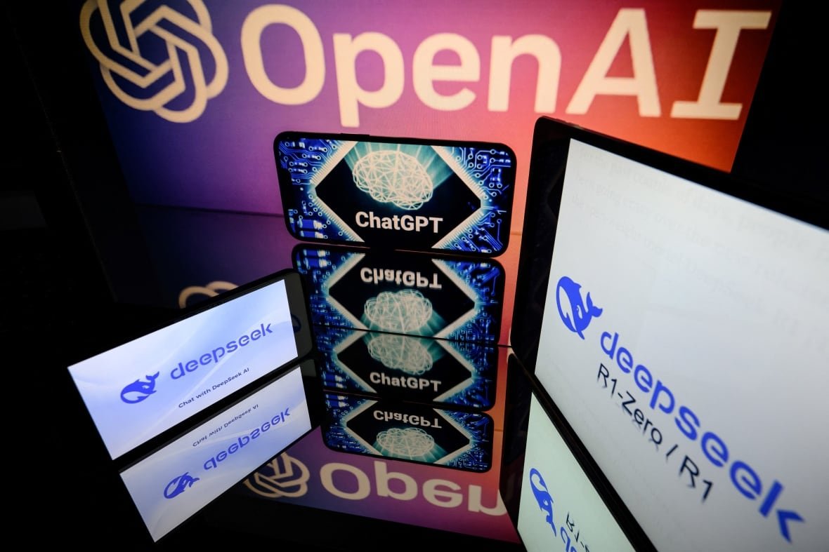2195926138 A smartphone with the ChatGPT logo full screen is reflected on a mirrored surface with "OpenAI" emblazzoned on the monitor backdrop and another smartphone to the left and tablet to the right show the "Deepseek" logo.