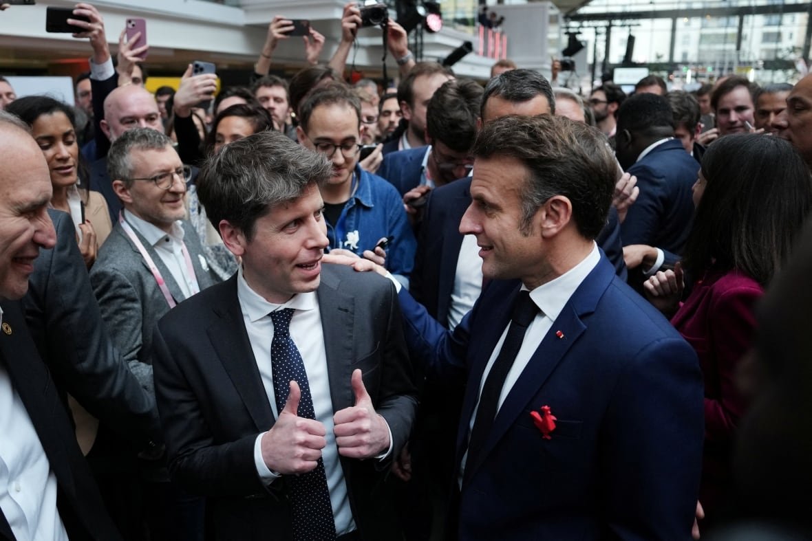 ai-summit Two men wearing suits are shown speaking to each other in a crowd.