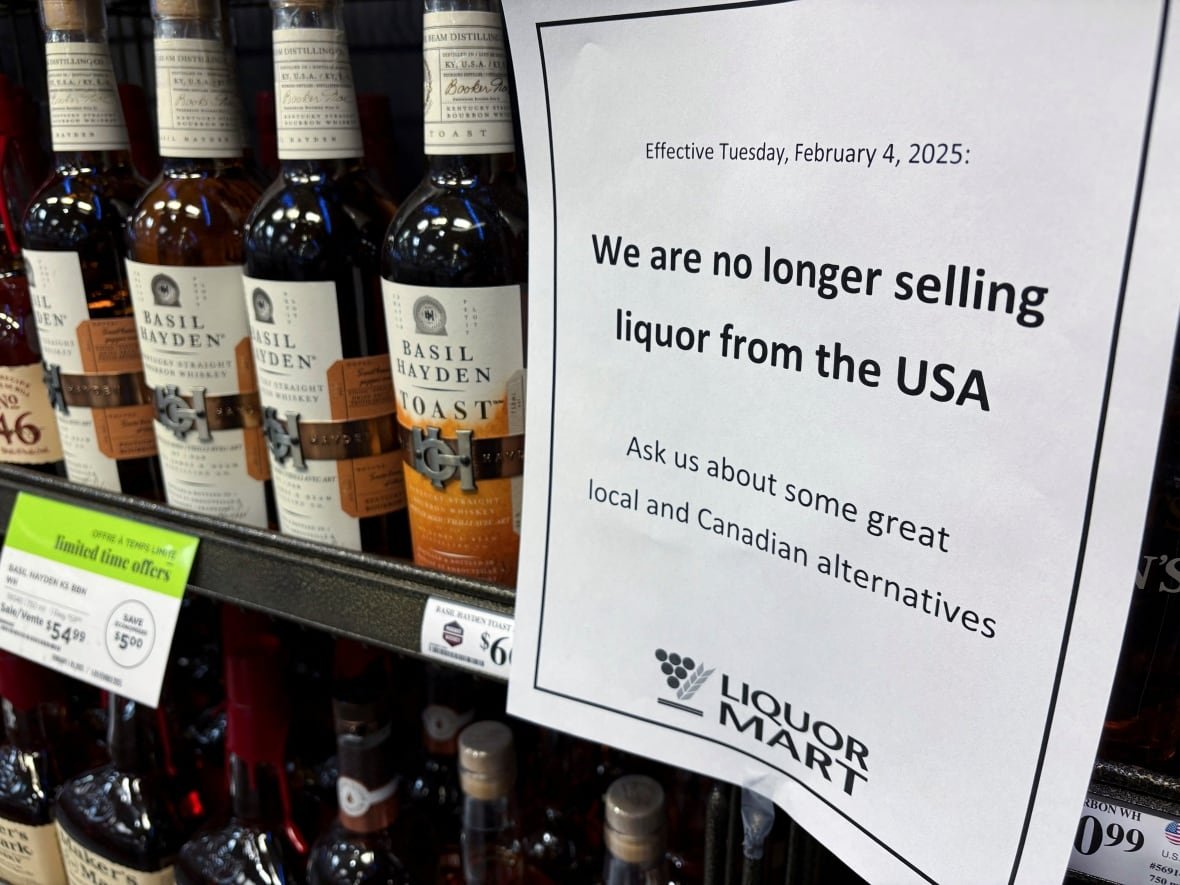 A sign in a white piece of paper is besides a group of bottles of wine.