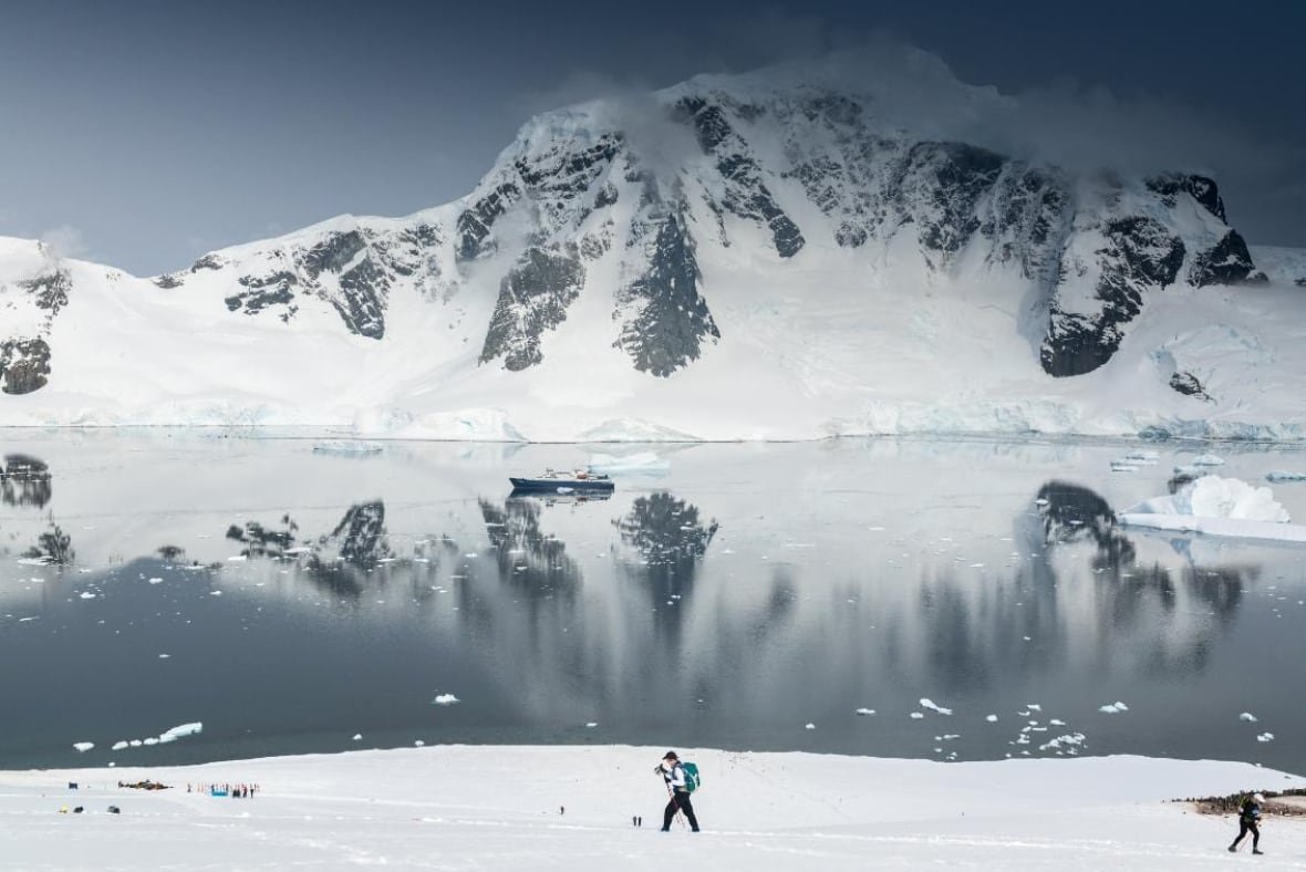 antarctic-ultramarathon-1 A woman walking in snow, with a mountain in the background.