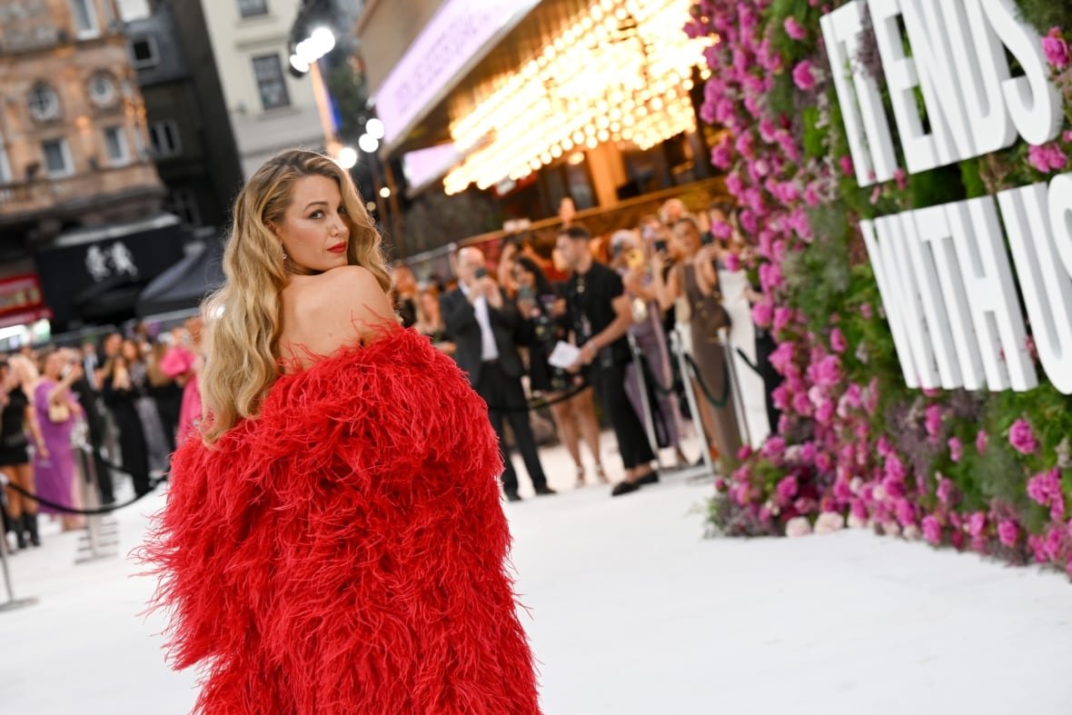 A person in a courtyard at a movie premiere looks back toward the camera.
