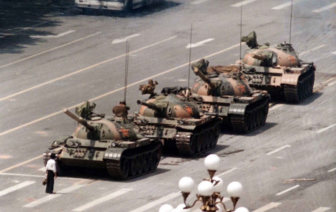 boy-on-beach-image-photo-gallery A lone man stands in the way of a column of tanks on a wide city road.