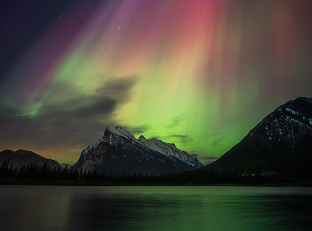 canadian-geographic-9 Northern lights dancing over a lake and mountain