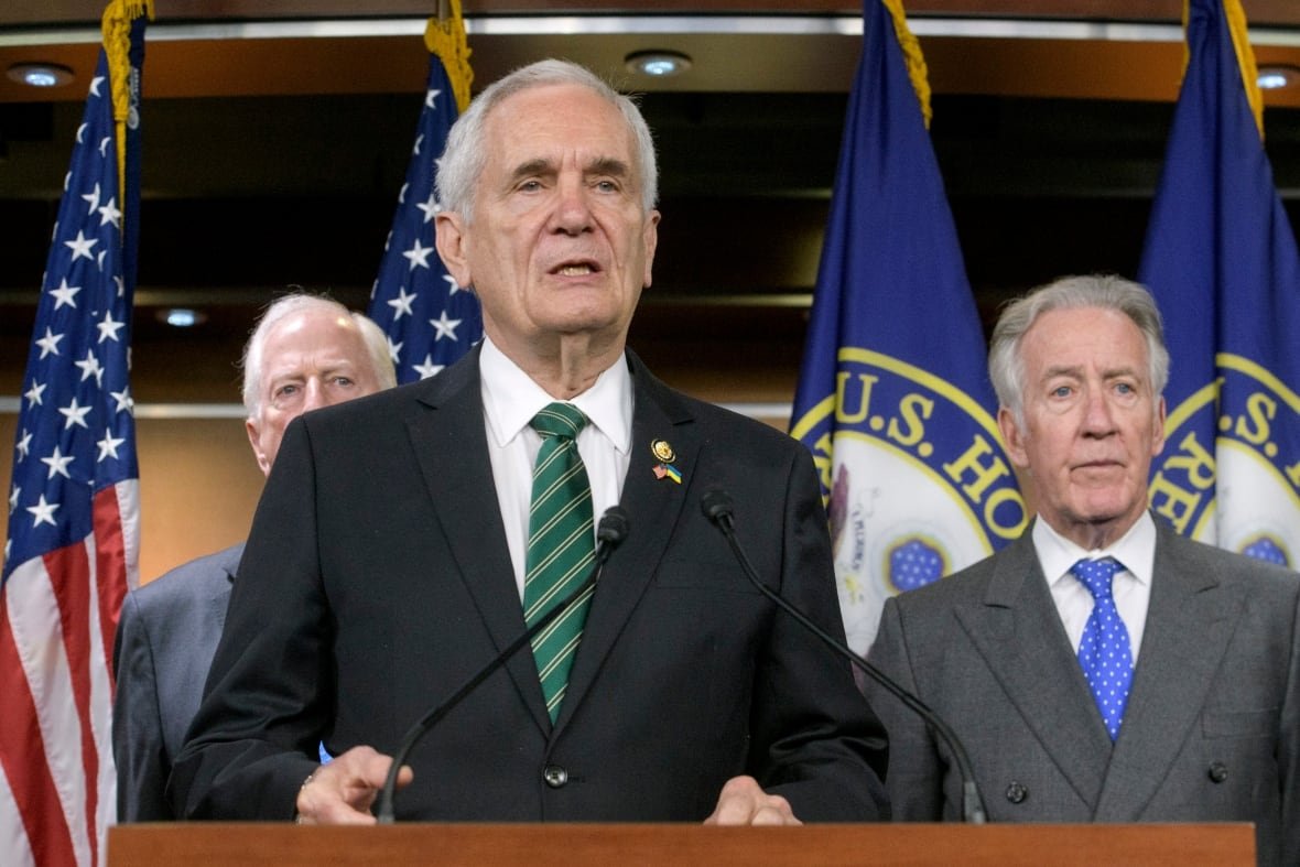 A man in a suit speaks at a podium.