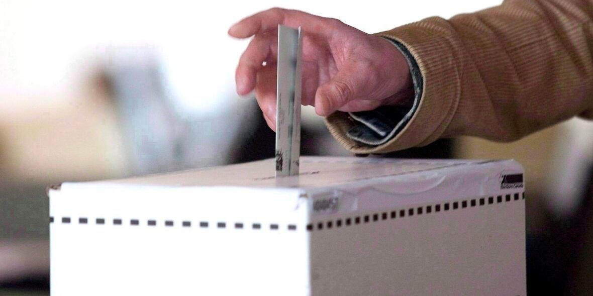 election-law-reform-20180528 A hand places a ballot into a ballot box.