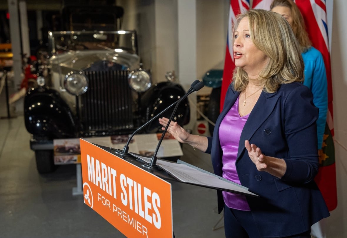 elxn-ont-20250203-1 Marit Stiles, seen from the side at a podium, with an antique car in the background.