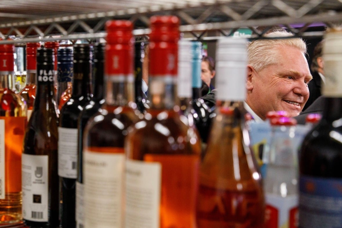 ford-convenience-store-alcohol-sales A white-haired man seen through racks carrying bottles of wine at a convenience store.