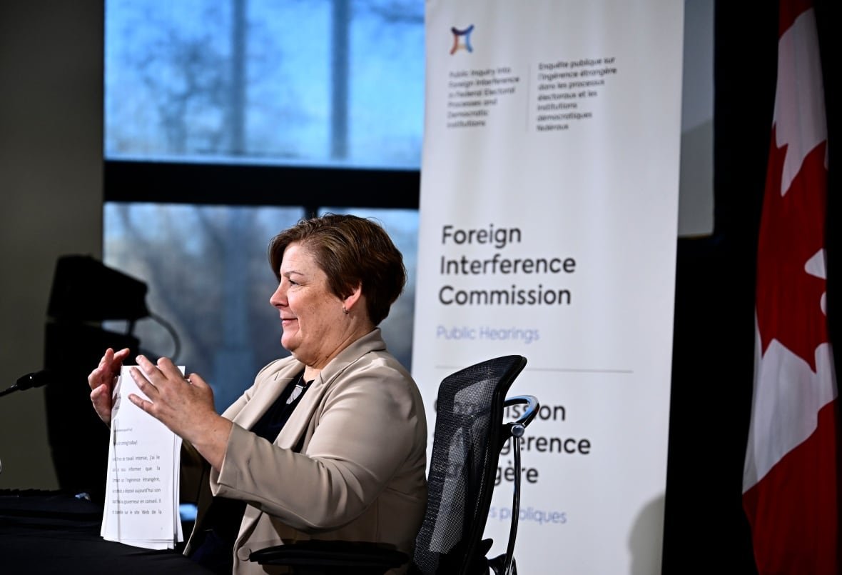 foreign-interference-20250128-4 A woman shuffles paper at a desk.