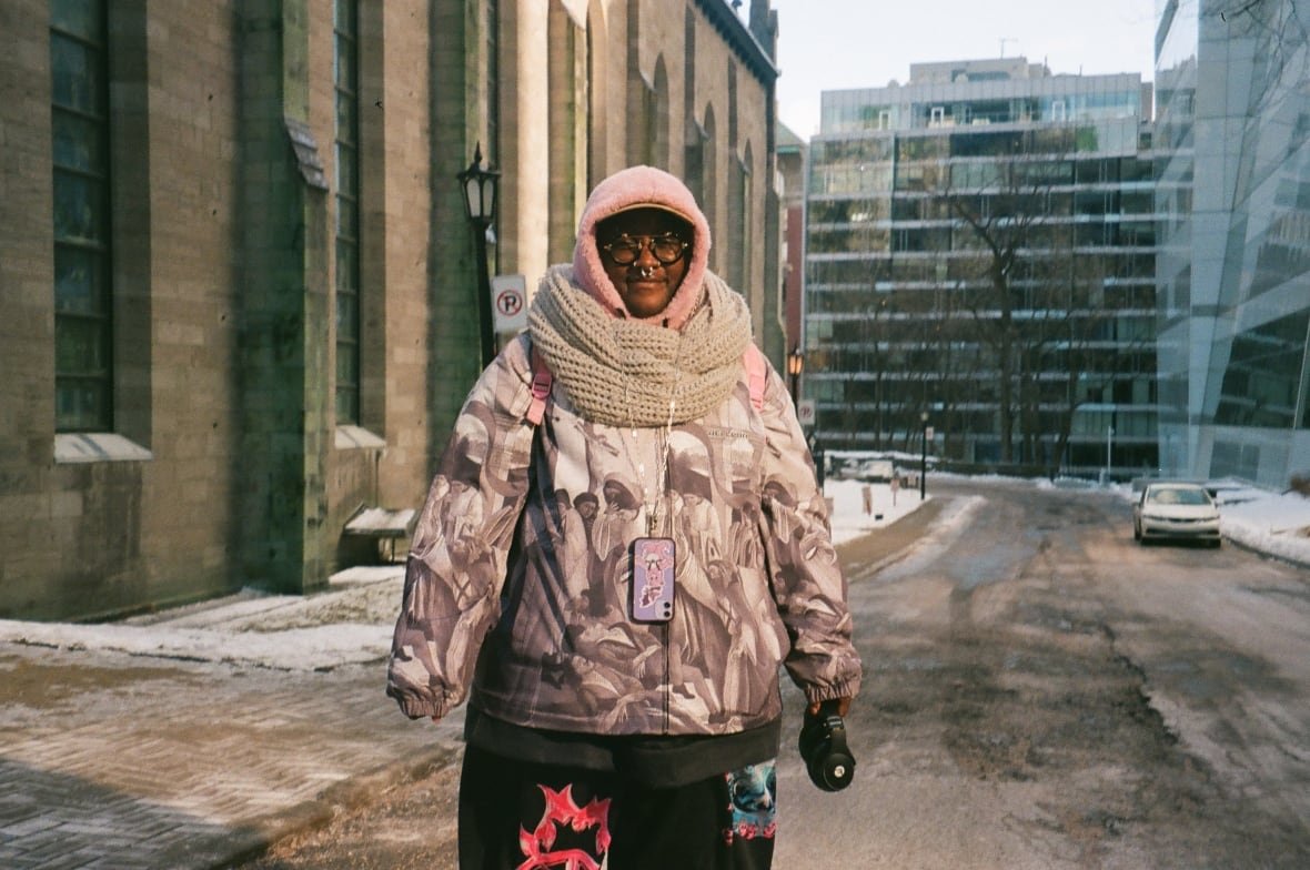 A person dressed in colourful clothing stands in front of a church in winter.