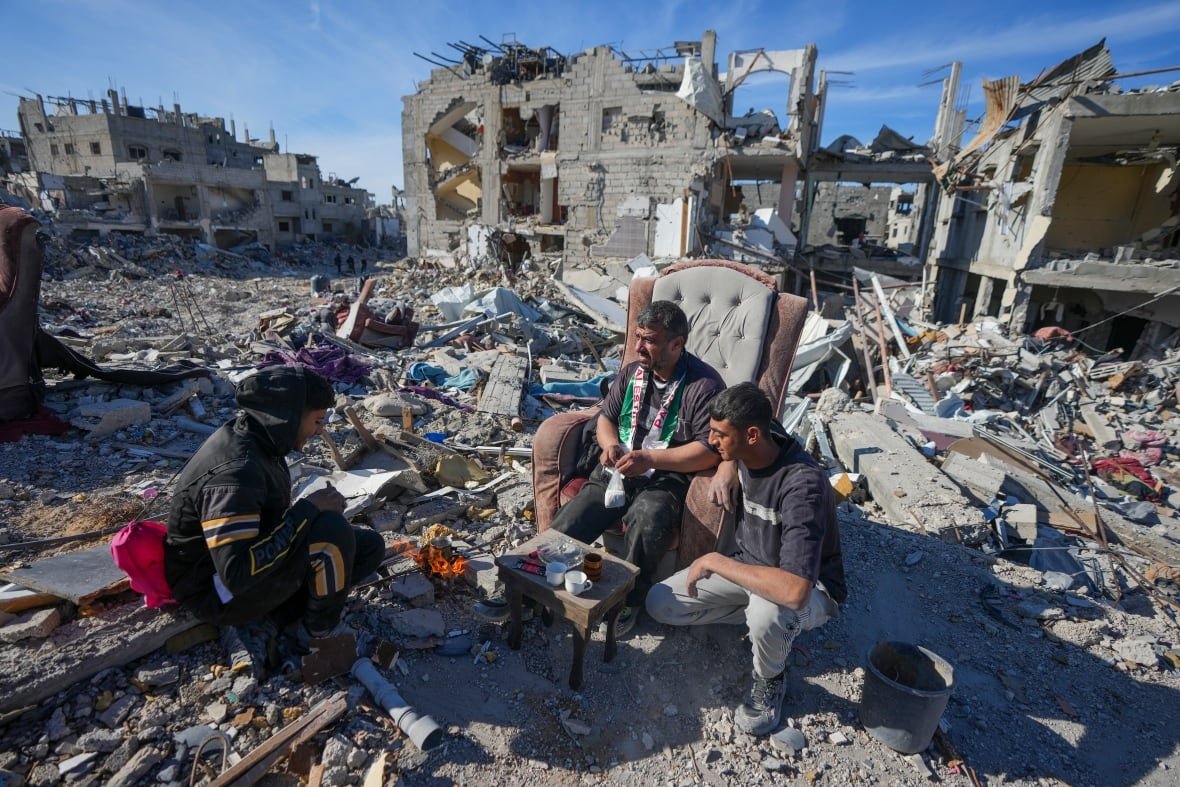 Men sit on a couch atop the rubble.