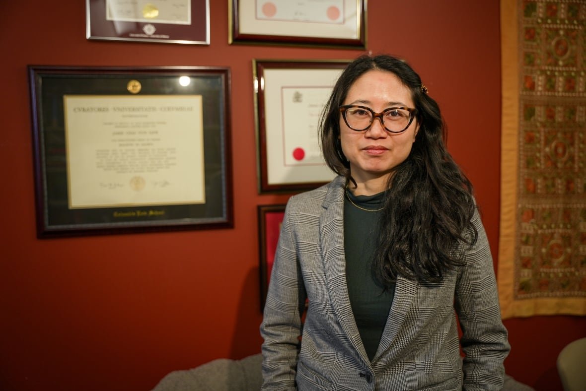 a woman standing against a wall in her office.